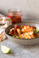 a bowl of fried rice with kimchi and shrimp on a light table