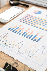 Business charts, mobile phone and stationery on beige background