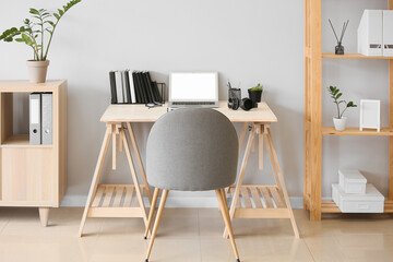 Interior of room with wooden standing desk and shelf unit near white wall