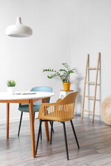 Dining table and chairs near white wall in room