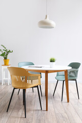 Dining table and chairs near white wall in room interior