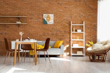 Stylish interior of dining room with modern furniture near brick wall