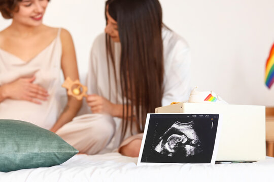 Sonogram image and box with baby stuff on bed, closeup