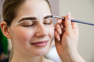 The master draws the shape of the eyebrows with white paint before coloring. 
