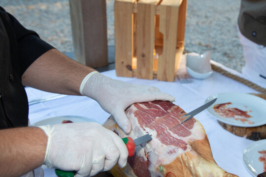 red ham cut by hand chef professional cutter carving slices from whole bone in serrano ham