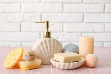 Set of bath supplies with candles on table near brick wall