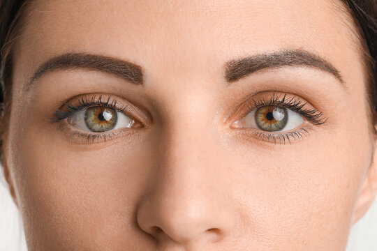 Young woman with beautiful hazel eyes on white background, closeup