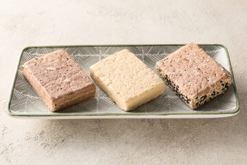 Plate with pieces of tasty sesame halva on light background