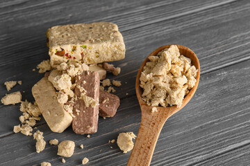 Spoon with crushed sesame halva on dark wooden background, closeup