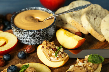 Wooden board of tasty apple wedges with nut butter, closeup