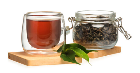 Glass cup of black tea and jar with dry leaves on white background