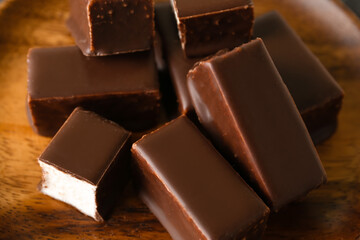 Wooden plate with tasty bird's milk candies, closeup