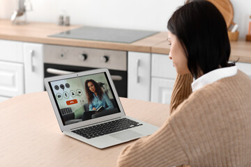Upset young woman video chatting with psychologist in kitchen
