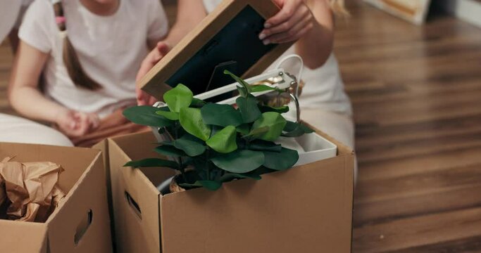 Close up shot selective focus on young family parents and preschooler kids sitting on floor in new modern apartment moving in process concept mother taking frame with phoro showing to family.