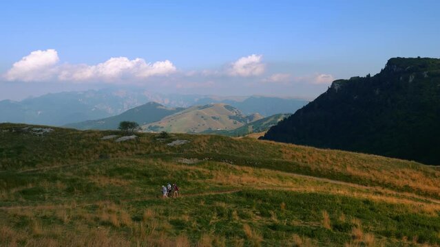 A group of active healthy sport people hiking on mountain top in the alps mountains on panoramic Monte Baldo at Garda Lake and Verona in Italy, Valpolicella wine and vinery area sunset.