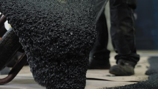 Worker dumping the tar from the wheelbarrow on the surface where he is working