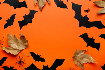Frame made of paper bats and autumn leaves on color background. Halloween celebration