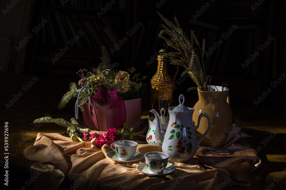 Wall mural tea cups and a teapot fanned out on a table against a dark background