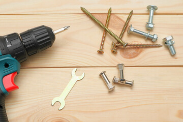 set of tools on wooden table, a electric screwdriver with a set of drill bits and screws with bolts. work tool on wooden background. Hand tool closeup