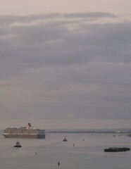 Luxury Cunard ocean cruiseship cruise ship liner Queen Victoria arrival into port of Southampton, England during early morning dusk twilight hour