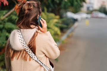 Woman talking on smartphone, back view, with space for text or design concepts.