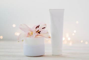 Beauty products bottles with garland lights and flowers. Holiday gift cosmetic concept