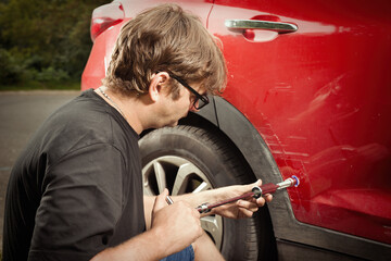 Car owner working on a dent repair with reverse hammer and glue - obrazy, fototapety, plakaty
