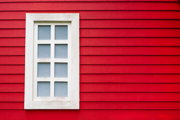 old white window frame on red decorative wooden wall panel with copy space, selective focus on the window