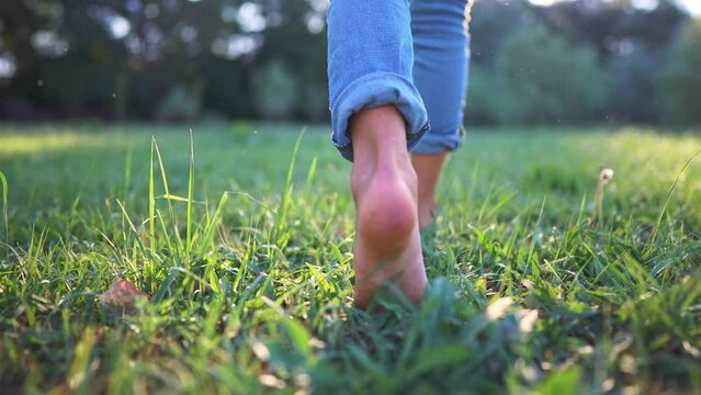 bare feet walking on the grass. a teenager girl takes off her shoes walking bare bare feet on the grass in the park in summer. happy family kid concept. bare feet close-up stepping on dream the grass
