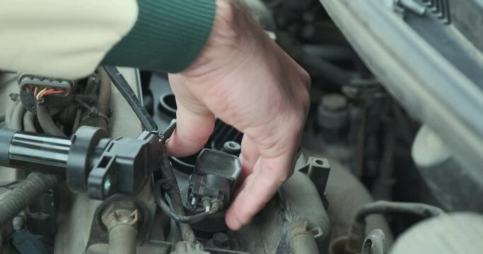 Man changing spark plugs of the car, takes out the candle holder. Close-up, machine maintenance, wear consumables.