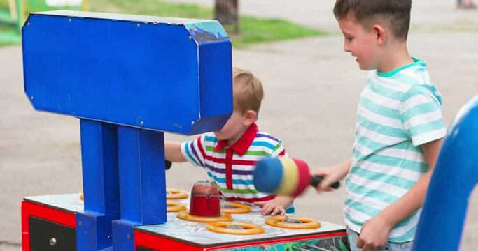 Children playing whack a mole arcade game at an amusement park.