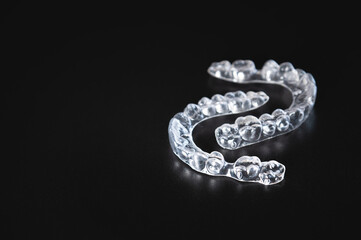 pair of transparent braces lies on a black background. orthodontics, bite correction and cometic dental care