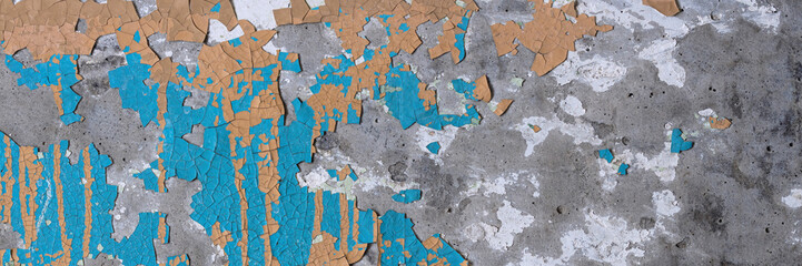 Peeling paint on the wall. Panorama of a concrete wall with old cracked flaking paint. Weathered rough painted surface with patterns of cracks and peeling. Wide panoramic grungy texture for background