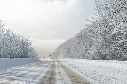 Scenic view of car alone car on curve turn beautiful mountain forest cpuntry woods highway road at cold snowy sunny weather winter day. Wintry frosty route landcape. Travel season journey trip drive