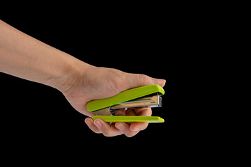 Hand and green stapler isolated on black background