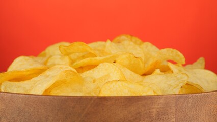 Potatoes chips in wooden bowl, isolated on red background