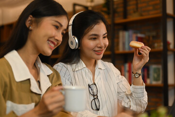 Happy young asian women sitting in coffee shop and using laptop computer. People and technology concept