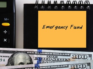 Dollars money, black notebook, calculator and yellow note with text written EMERGENCY FUND, smart financial planning goal to build fund to be safety net expenses in unplanned life crisis