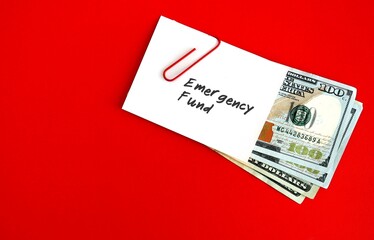 White paper note with text written EMERGENCY FUND clip with cash dollars money on red copy space background , smart financial planning to save money for contingency fund - for rainy day, future crisis - obrazy, fototapety, plakaty