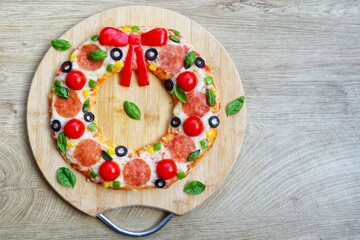 Christmas wreath pizza on wooden cutting board with wooden table background.Art food idea for...