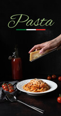 Pasta with tomato sauce and parmesan. White plate with spaghetti on a dark background with the word pasta. Hands grating Parmesan cheese on a spaghetti pasta. Traditional Italian food 