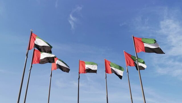 National symbol of United Arab Emirates flags in blue sky background. Seven UAE flags represent seven emirates  waving in wind. 