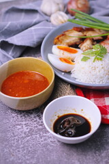 rice with red pork on top served with boiled egg, cucumber and crispy pork with dipping sauce and soy sauce served in the restaurant