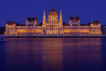 Budapeszt oświetlony budynek parlamentu Országház widziany z rzeki Dunaj po zachodzie słońca - obrazy, fototapety, plakaty