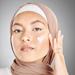 Muslim, beauty and skincare woman with cream on face product against a grey mockup studio...