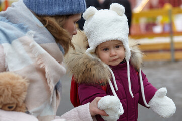 Obraz premium Mother and daughter are walking around the city on Christmas and New Year holidays. Parent and little child having fun outdoors