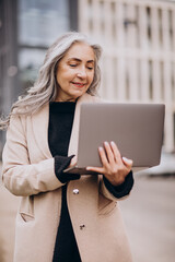 Elderly business woman holding laptop