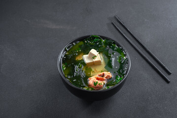 Asian salmon soup on black background. Top view