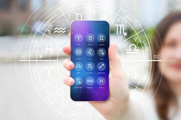 A woman's hand holds a smartphone with an astrological application, astro forecast for all zodiac...