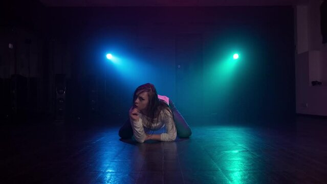 Woman dancing in dark studio with smoke and lighting. Artist performance. Blue and turquoise spotlights. Sensual female dancing. 4K, UHD